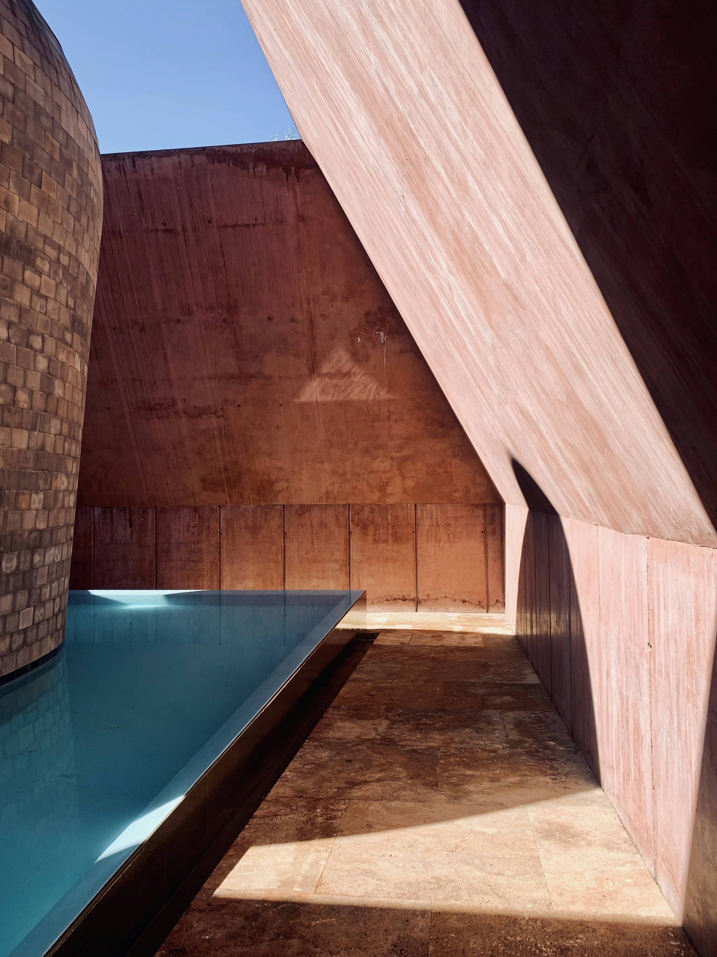 a long pool in a building with a sky background
