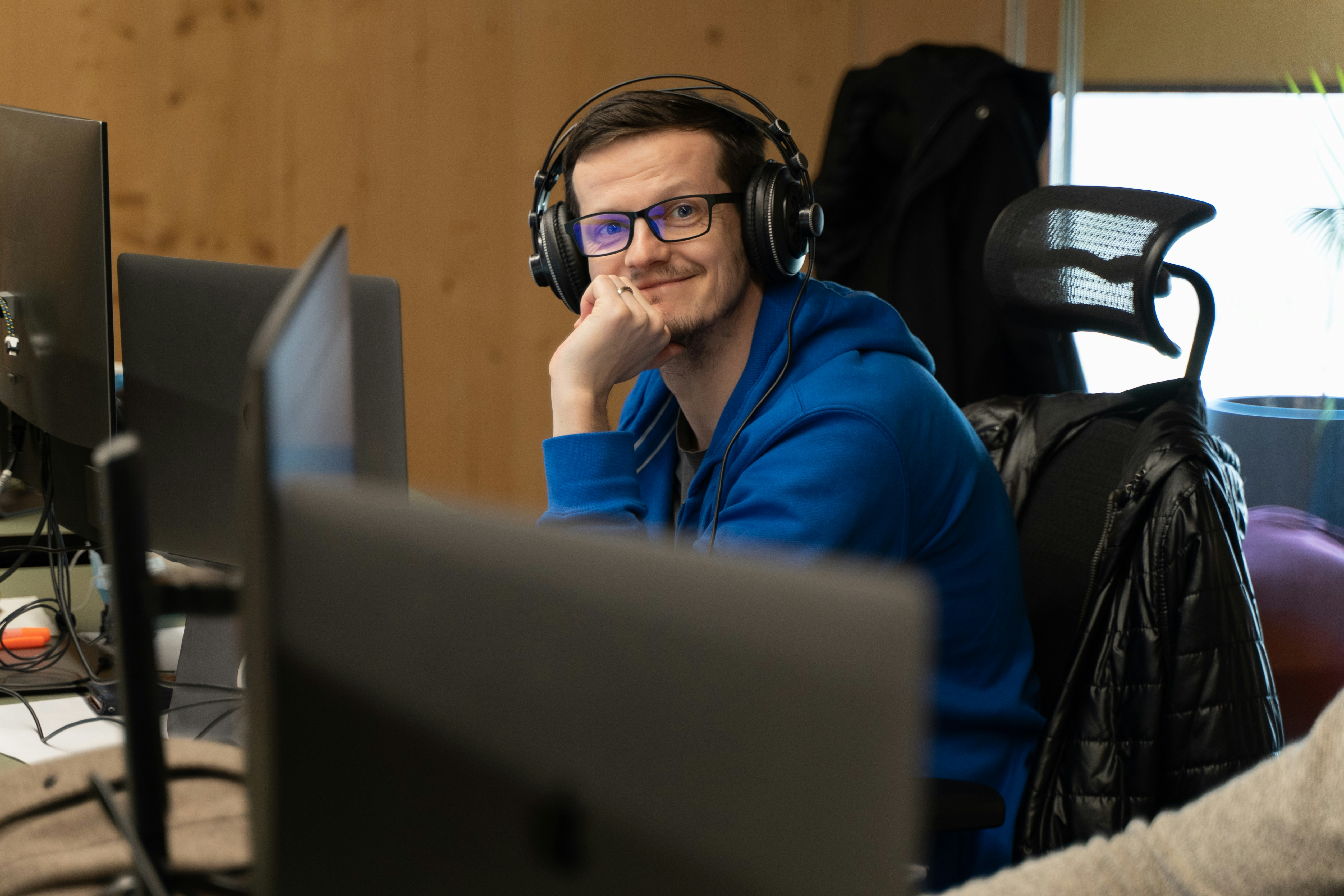 Seorang pria mengenakan headphone duduk di depan komputer