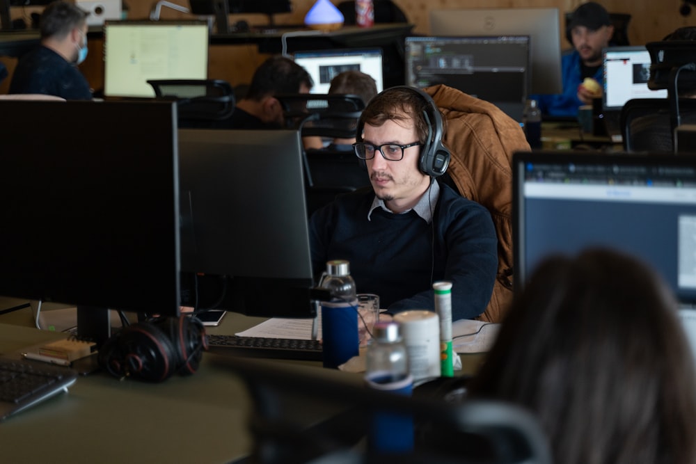 um homem usando fones de ouvido sentado na frente de um computador