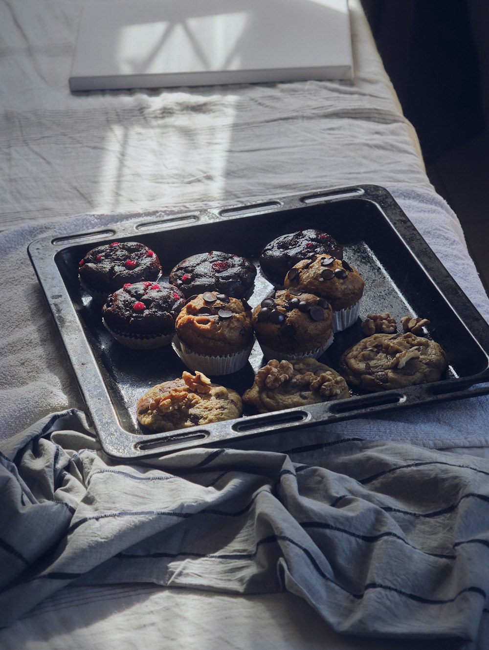 a tray of muffins sitting on top of a bed