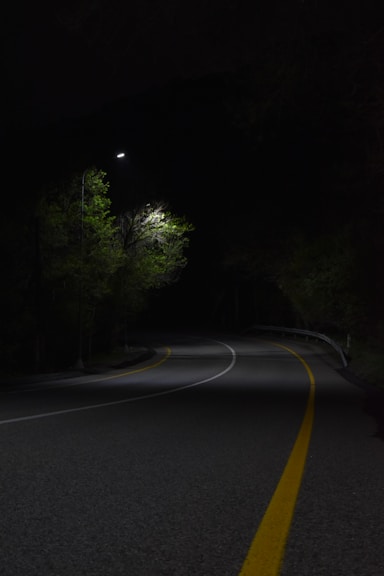 a dark road with a street light in the distance