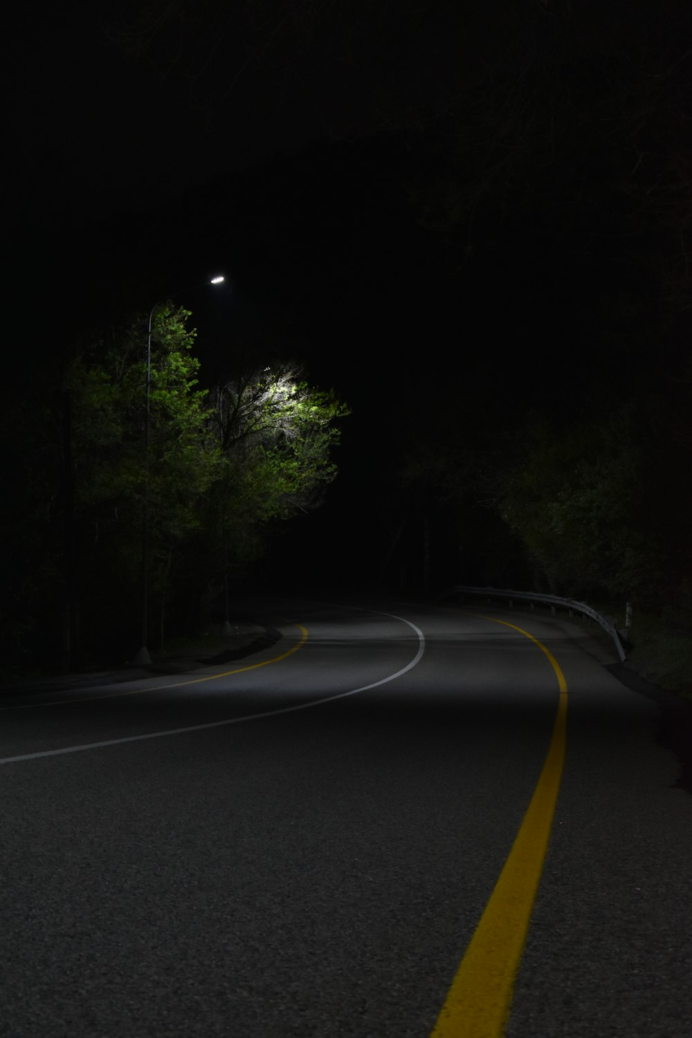 a dark road with a street light in the distance