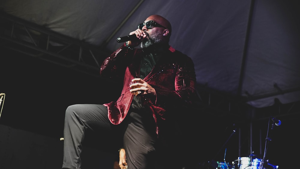 a man in a red jacket is singing into a microphone