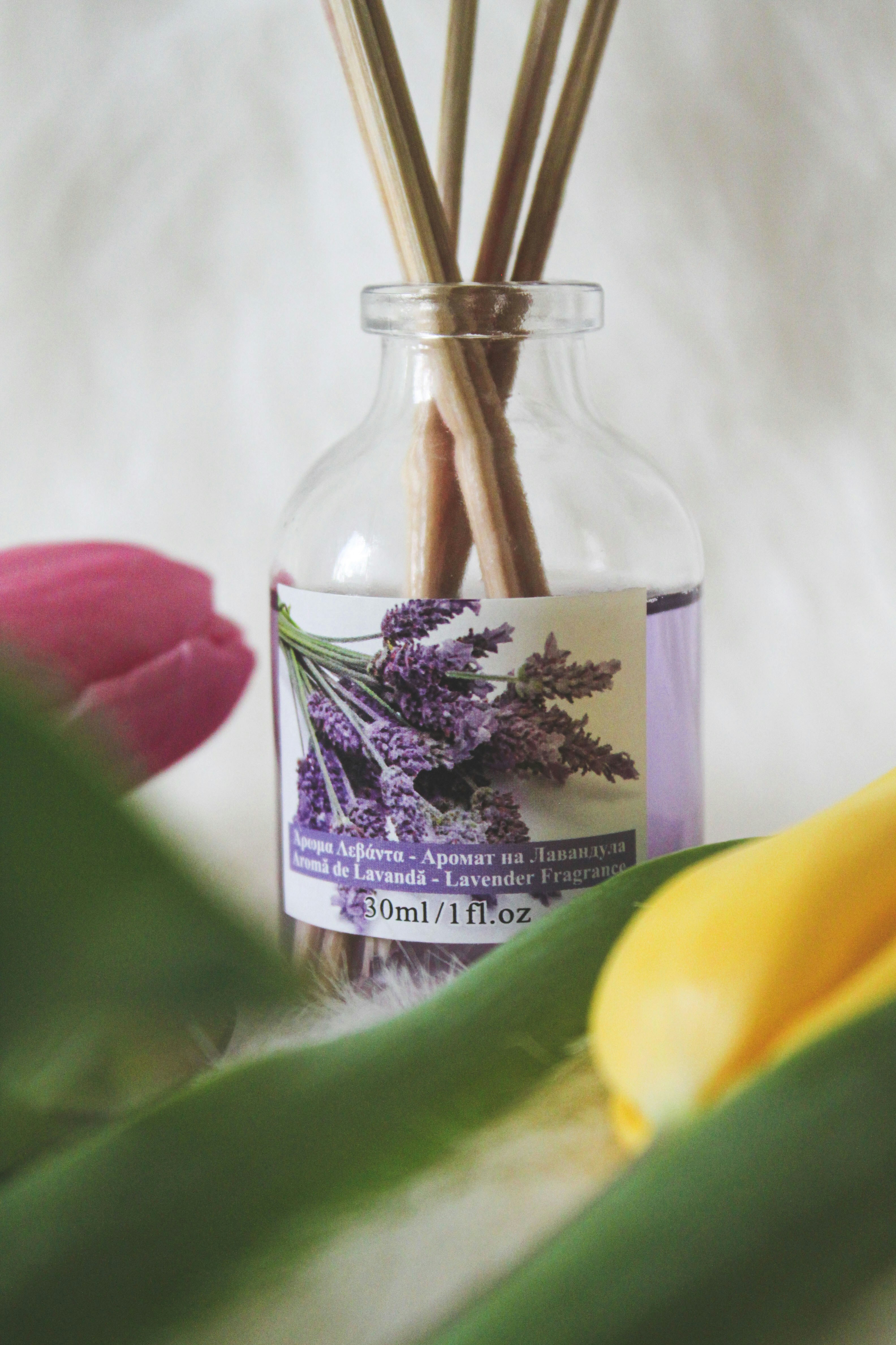 a glass jar filled with reeds next to a flower