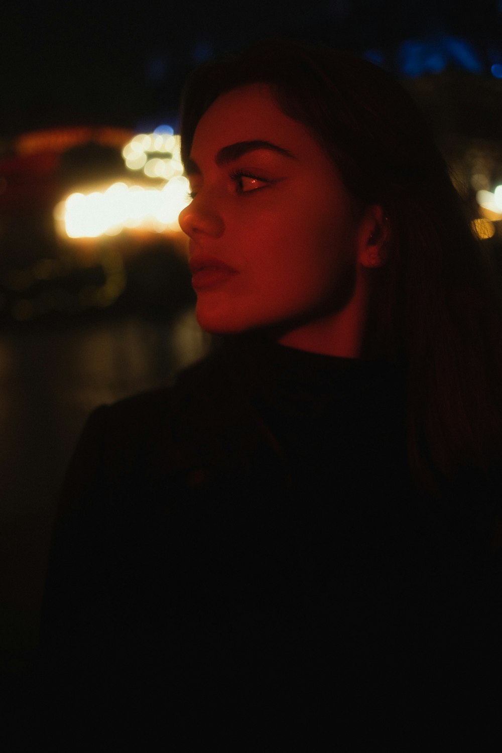 a woman standing in front of a city at night