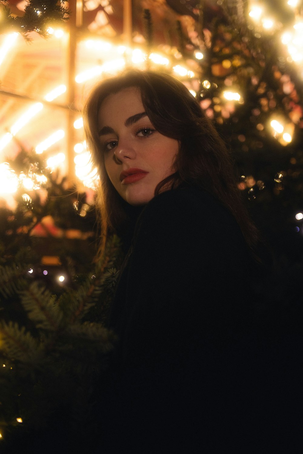 a woman standing in front of a christmas tree