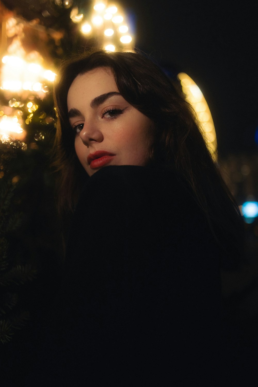 a woman standing in front of a christmas tree