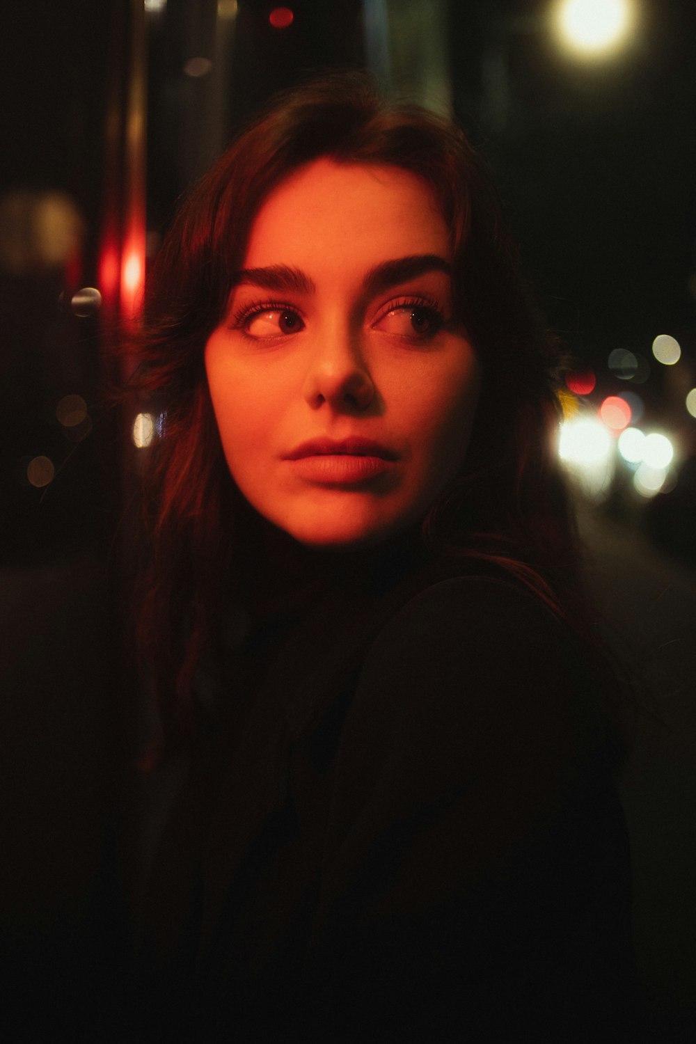 a woman standing on the side of a road at night