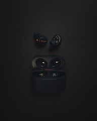 a pair of black earphones sitting on top of a black surface
