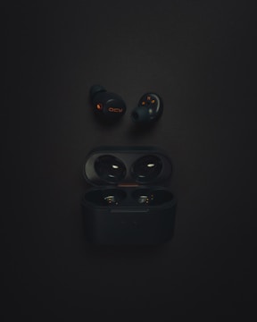 a pair of black earphones sitting on top of a black surface