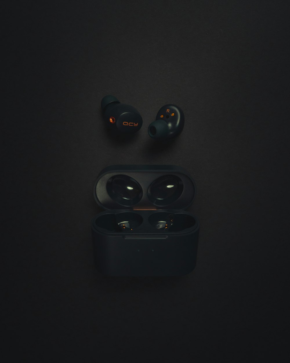 a pair of black earphones sitting on top of a black surface