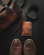 a pair of shoes, a wallet, and a belt laid out on a table