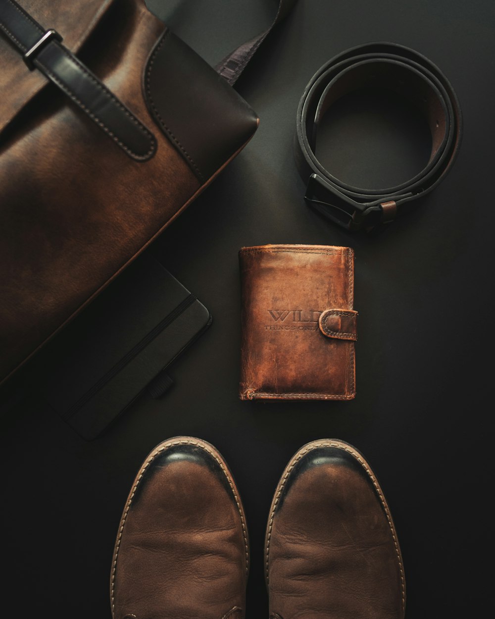 a pair of shoes, a wallet, and a belt laid out on a table