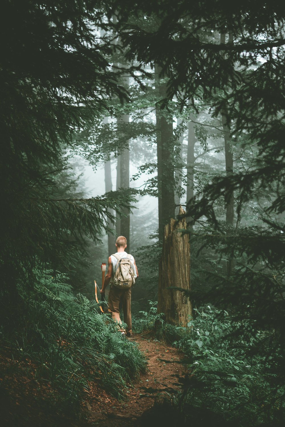 a man with a backpack walking up a trail in the woods