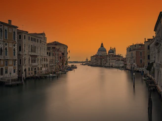 A winding canal in Venice reflecting historic buildings under a soft sunset.