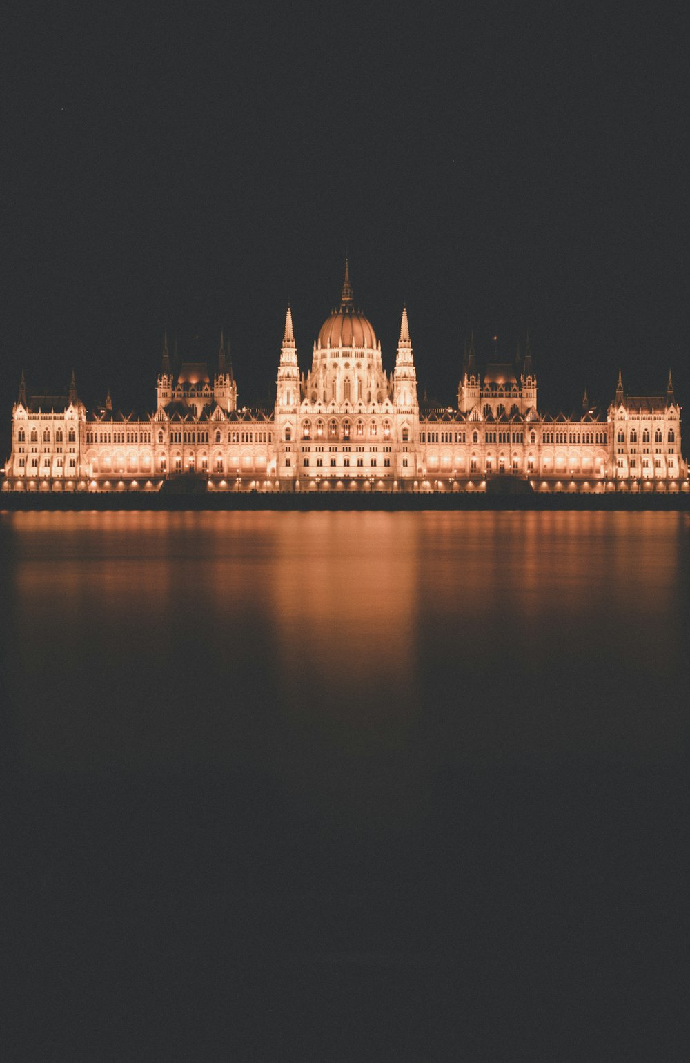 a large building lit up at night with water in front of it