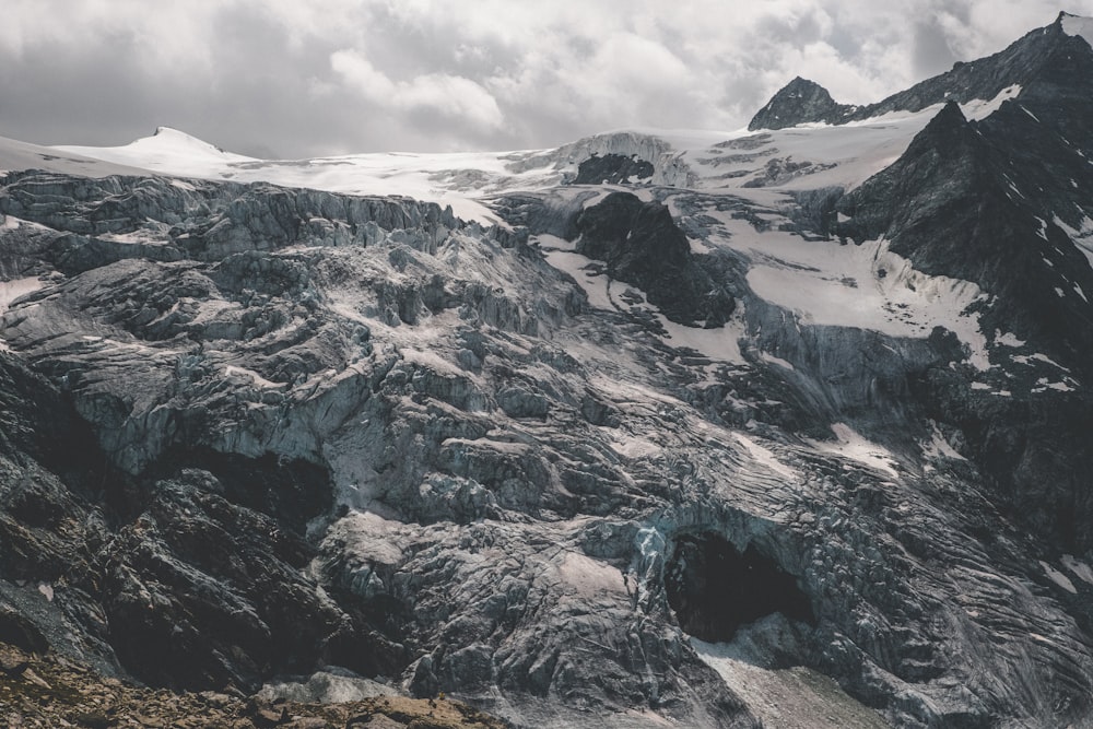 a mountain range covered in snow under a cloudy sky