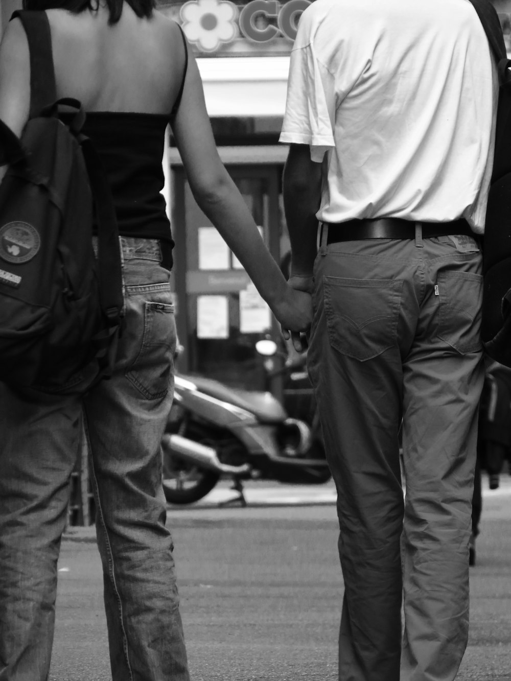 a man and a woman holding hands walking down the street
