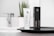 A white tube of activated charcoal deep pore cleanser labeled Vivalui stands next to its black box. Both are placed on a sleek dark tray, with a modern sink and faucet in the background, alongside a potted plant adding a natural touch.