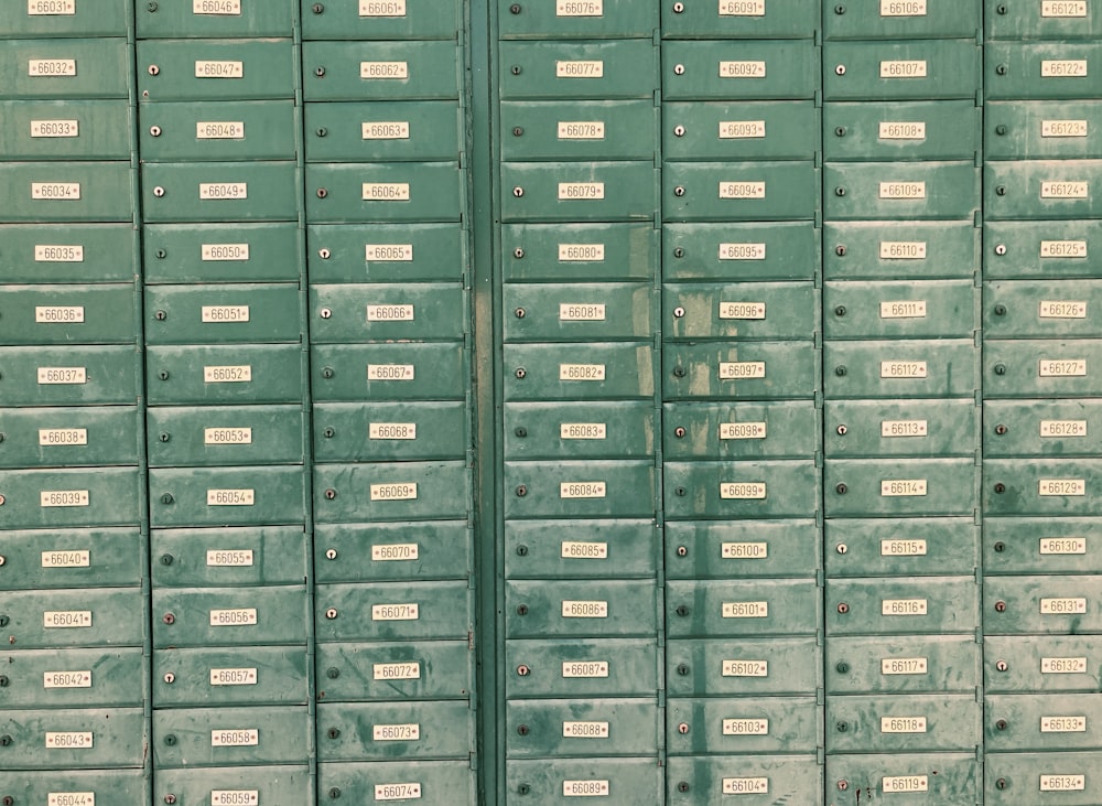 a row of green mail boxes with white labels on them