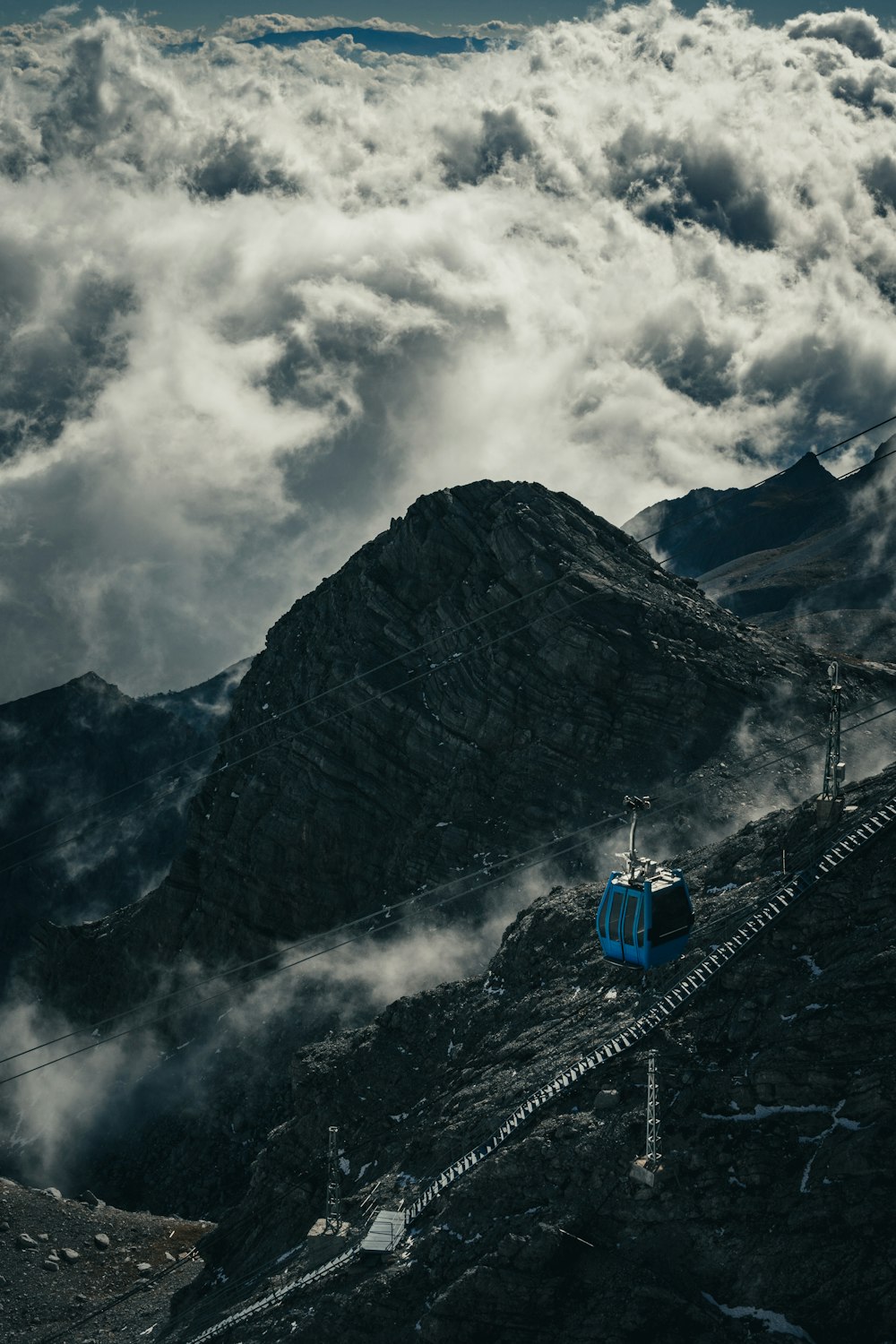 a blue train traveling down a mountain side