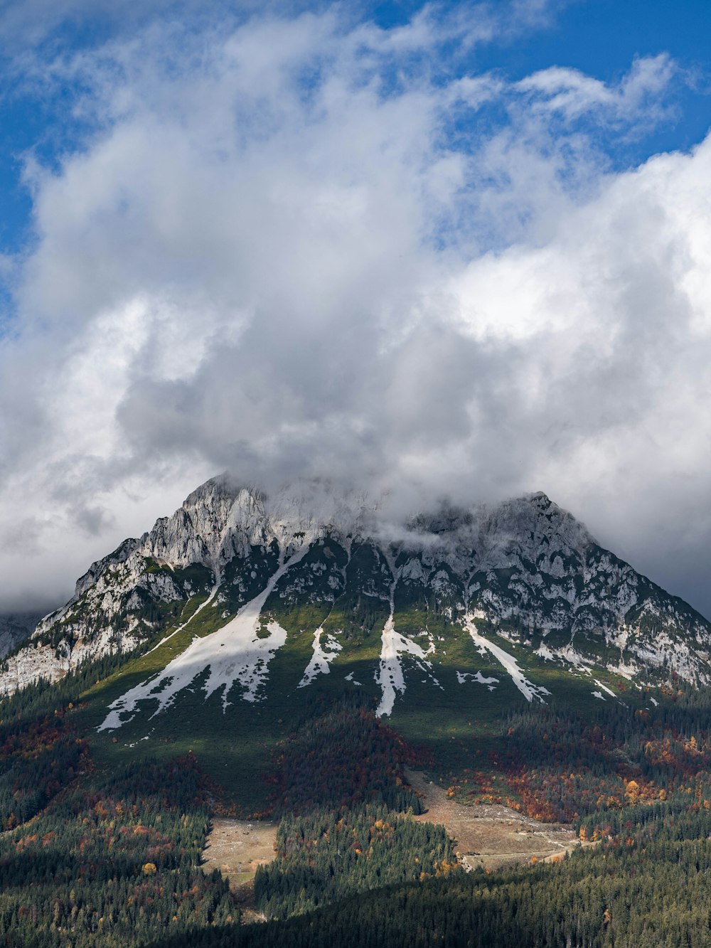 a mountain covered in snow under a cloudy sky