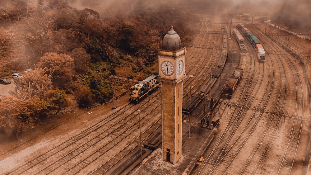 un'alta torre dell'orologio seduta sul lato di un binario ferroviario
