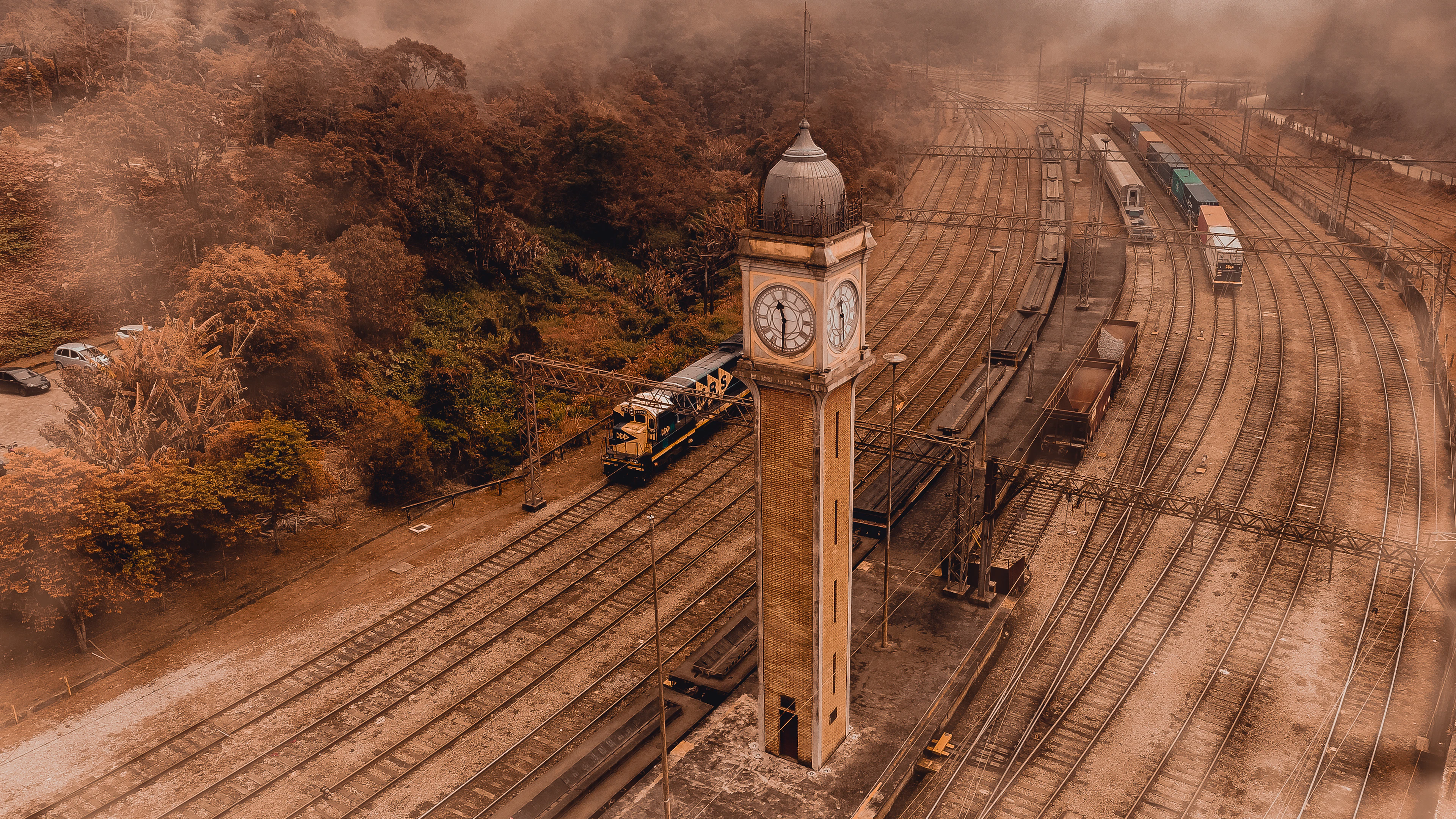 Aerial view of Paranapiacaba's clock tower and railway yard wrapped in golden morning fog.
