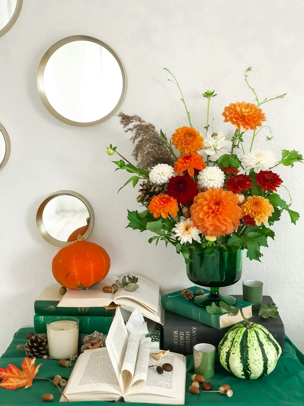 a green table topped with books and a vase filled with flowers