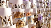 A collection of artistic prints, each depicting scenes of traditional village life, featuring desert landscapes, buildings, and people. They are arranged in an overlapping manner on display, with different color schemes and intricate designs visible.