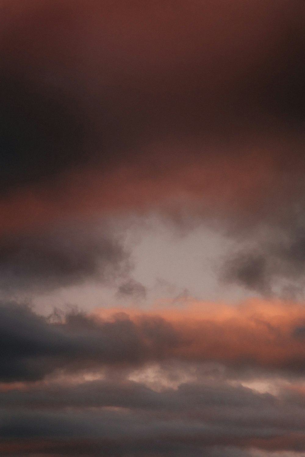 a plane flying through a cloudy sky at sunset