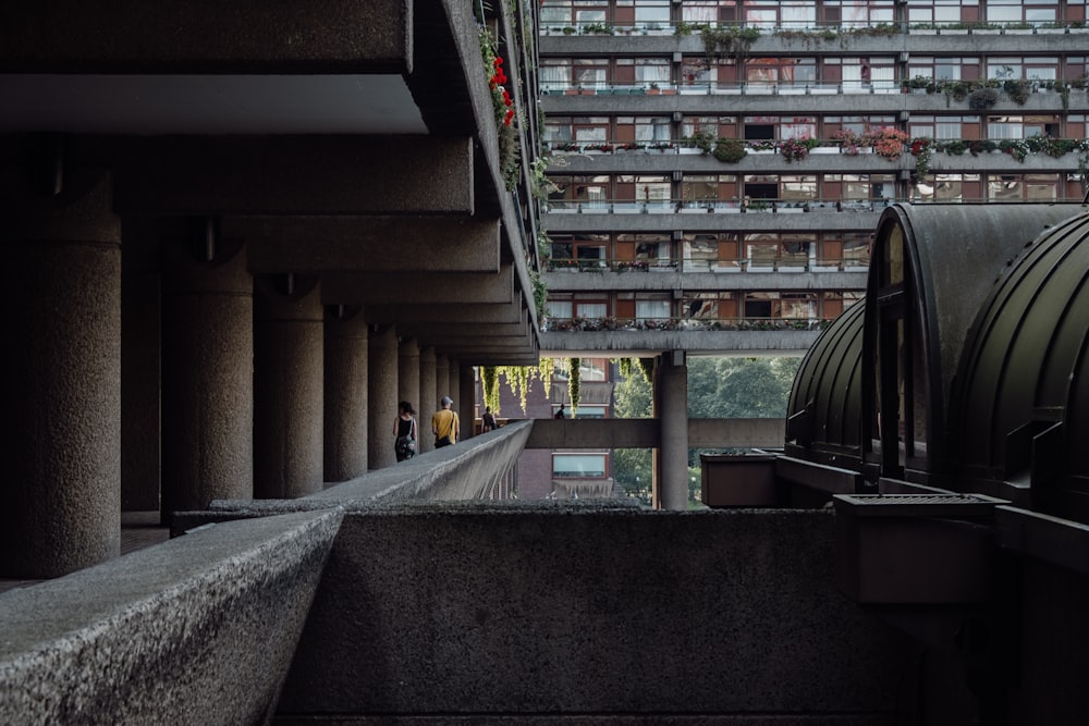 a group of people walking down a walkway next to tall buildings