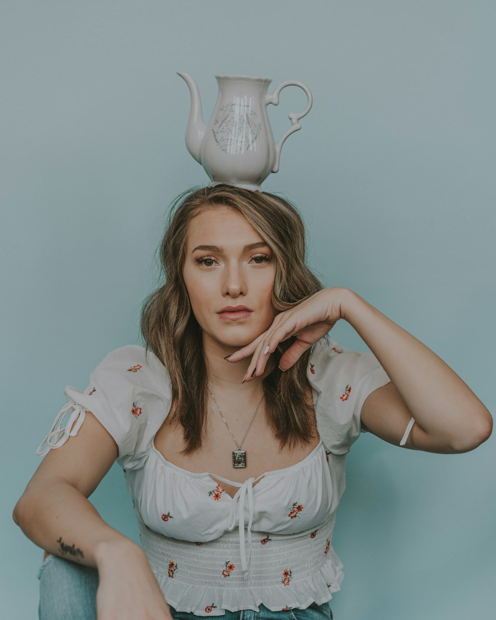a woman sitting down with a teapot on her head