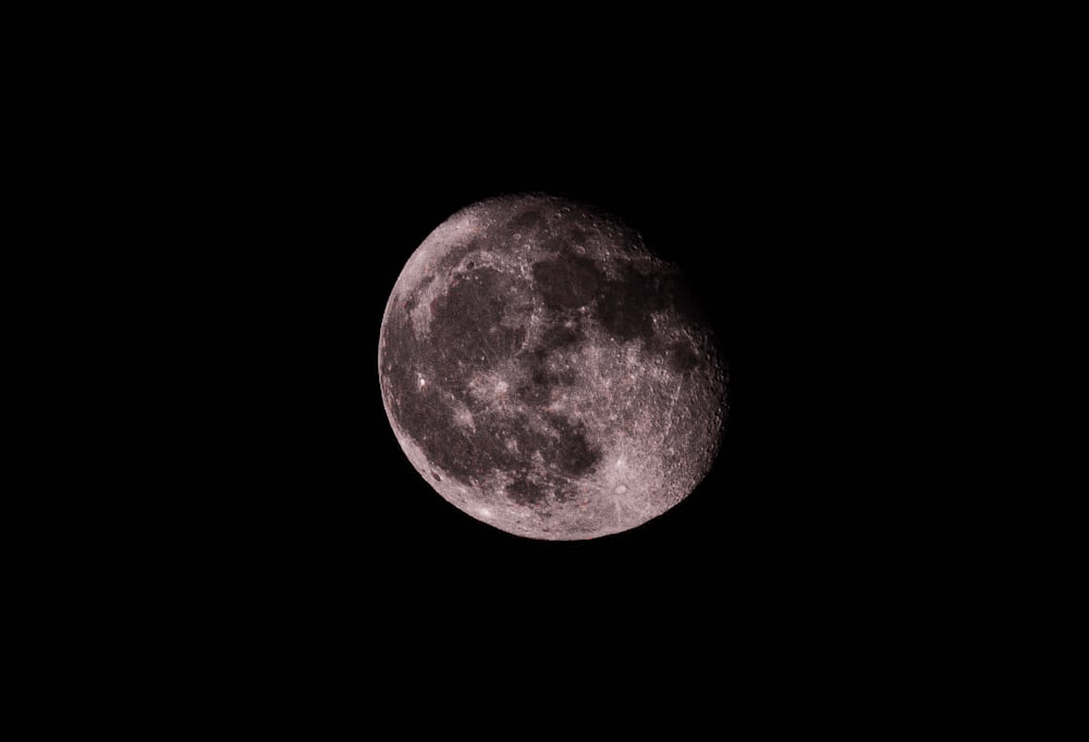 a full moon is seen in the dark sky