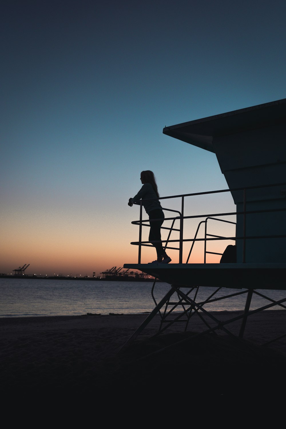 a woman standing on top of a metal railing next to a body of water