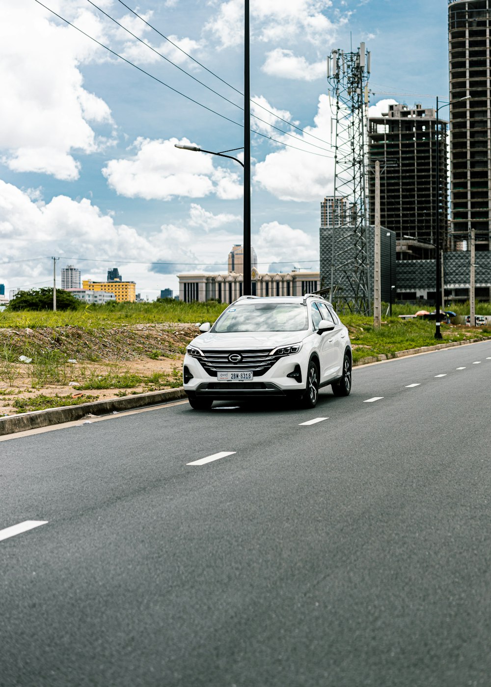 a white car driving down a street next to tall buildings