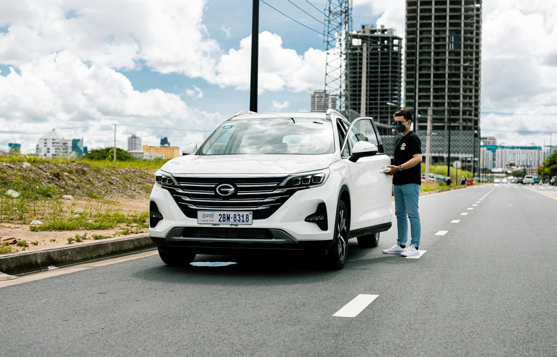 a man standing next to a white car on the side of a road