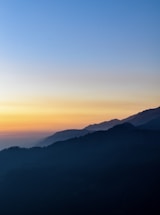 the sun is setting over a mountain range