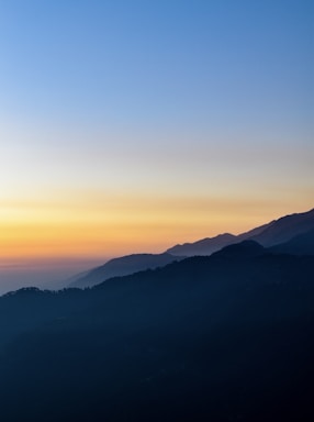 the sun is setting over a mountain range