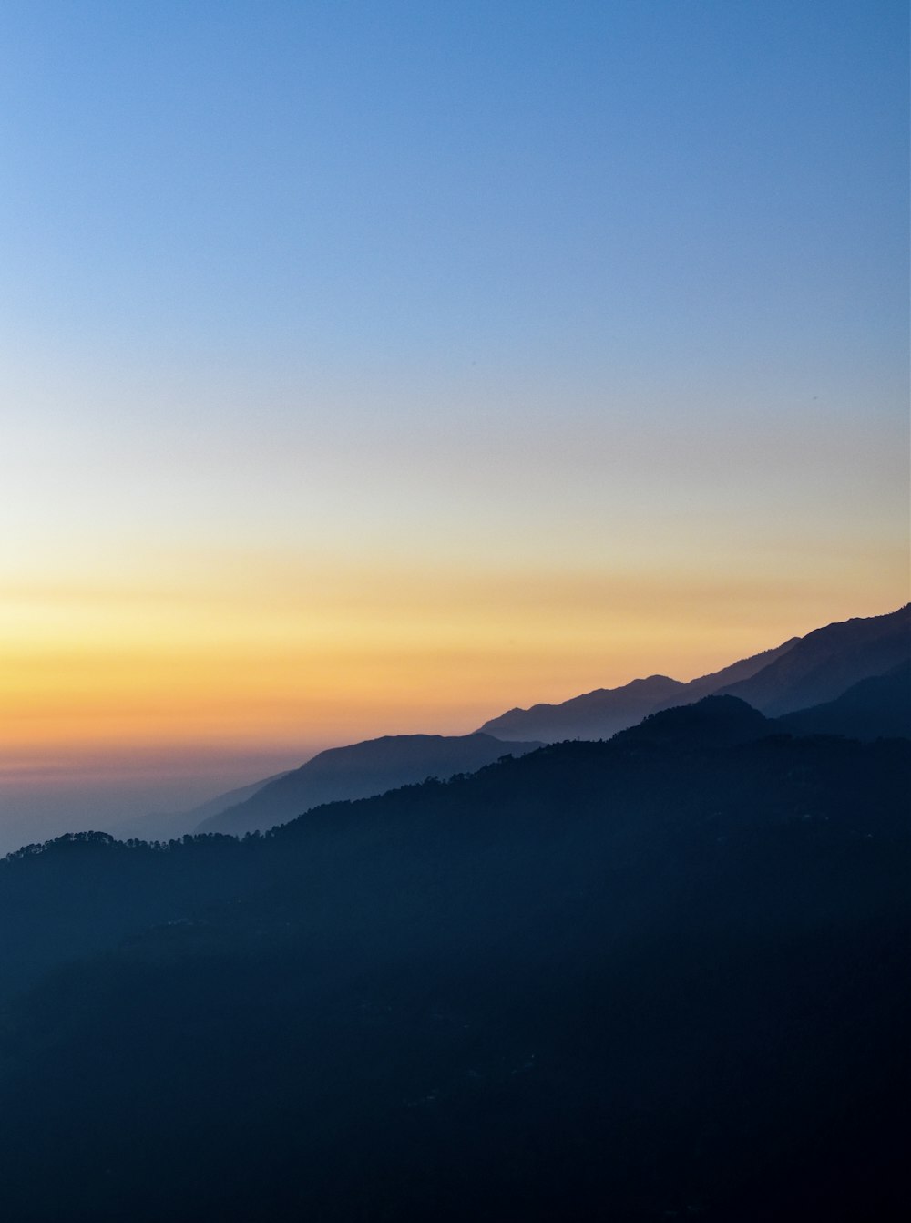 the sun is setting over a mountain range