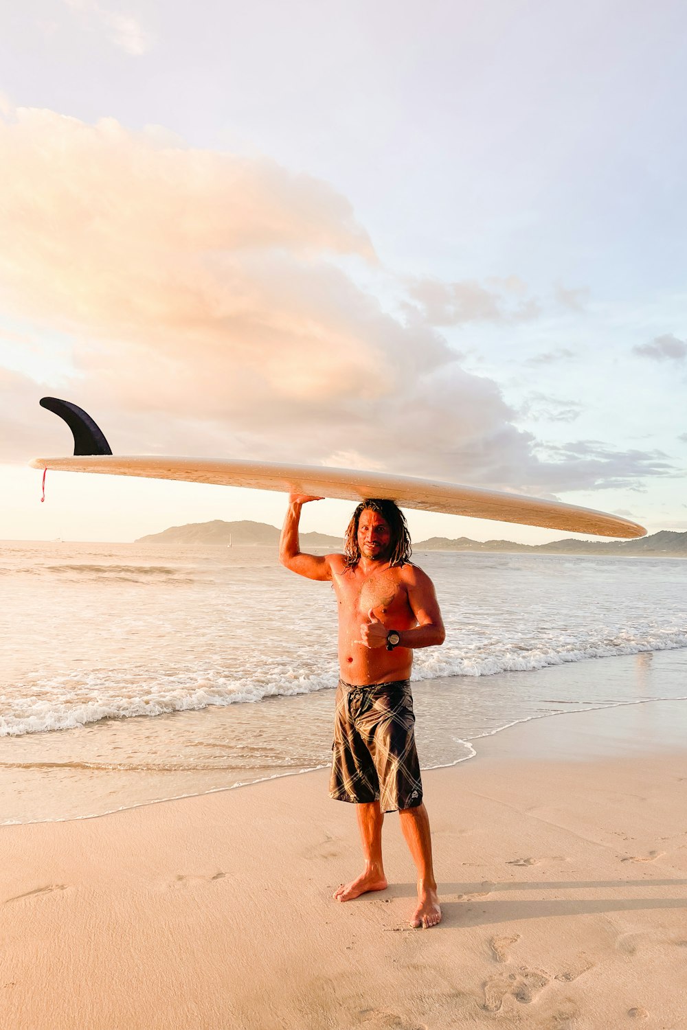 a man standing on a beach holding a surfboard