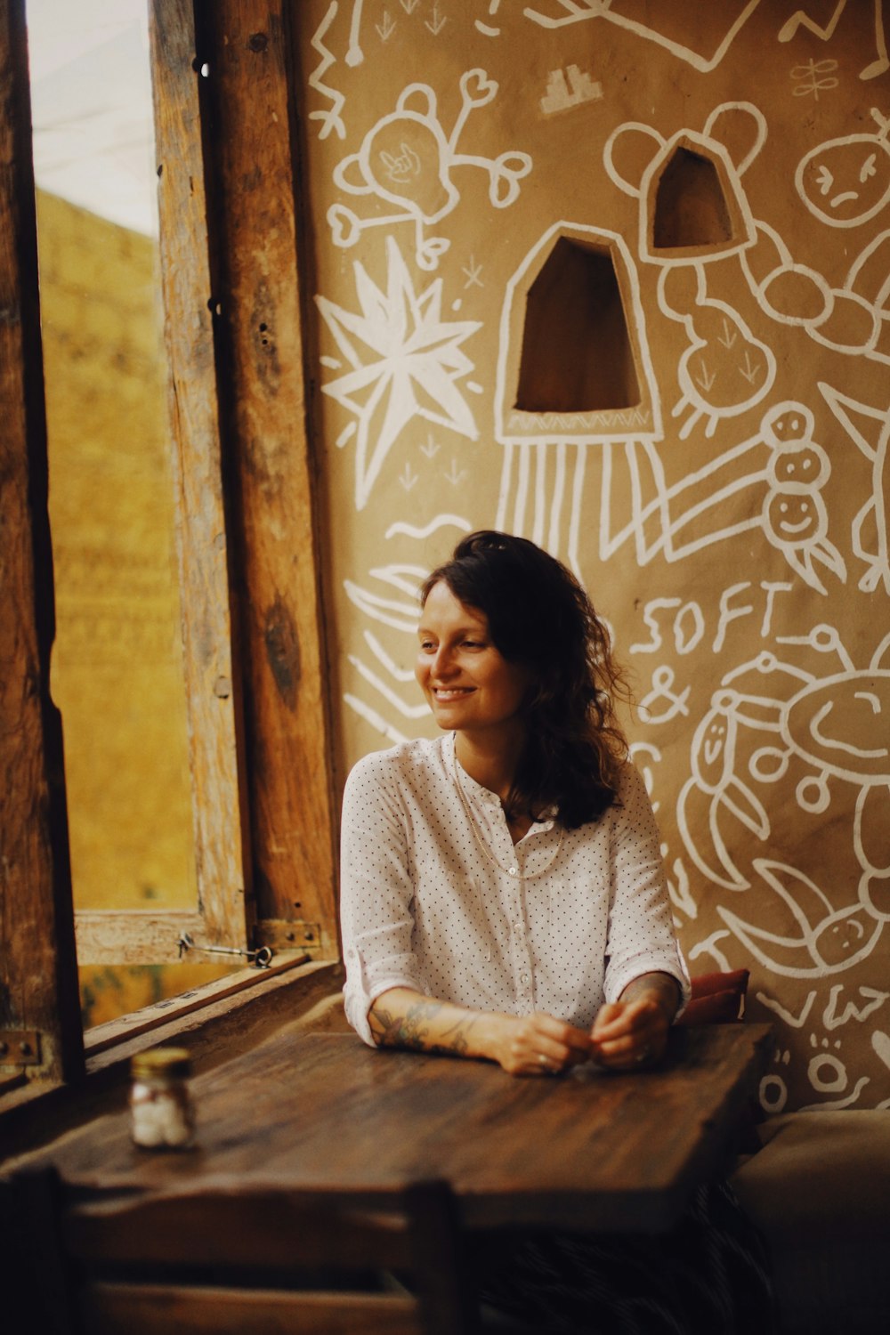 a woman sitting at a table in front of a window