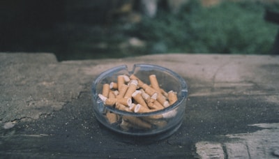 un cendrier rempli de mégots de cigarette est posé sur une table