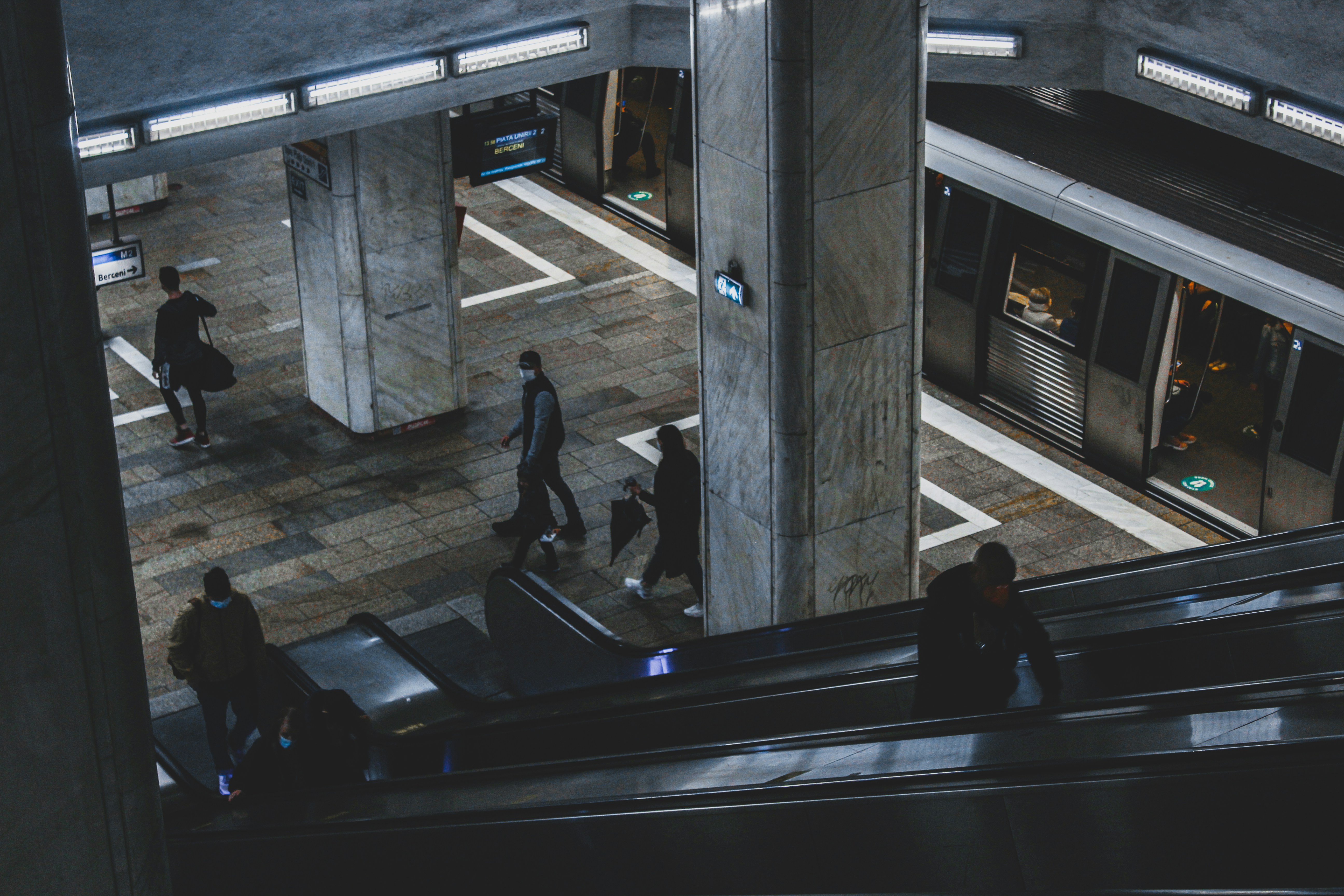 a group of people walking down an escalator, Metro Station in Bucharest, Romania
