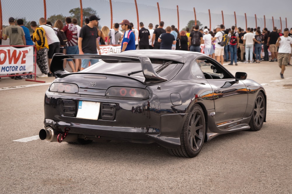 a black sports car parked in front of a crowd of people