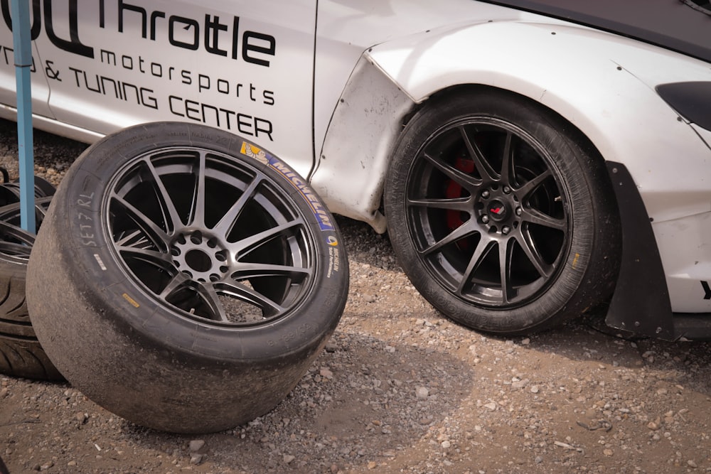 a white car parked next to a pile of tires