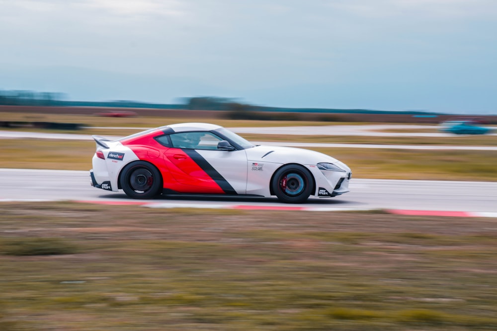 a red and white sports car driving on a track