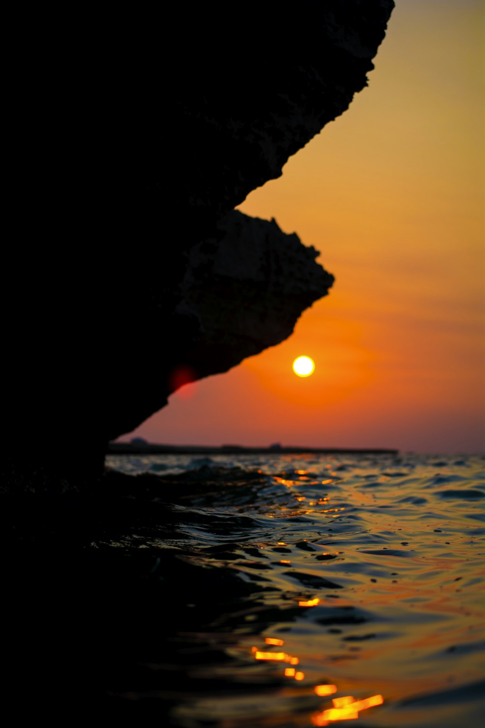 o sol está se pondo sobre o oceano com um afloramento rochoso