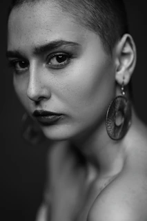 Portrait of a strong woman with a shaved head and intense gaze, showcasing her white mouth guard with a modern, edgy vibe.