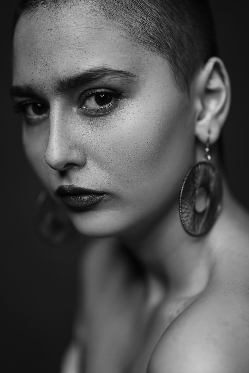 a black and white photo of a woman with earrings